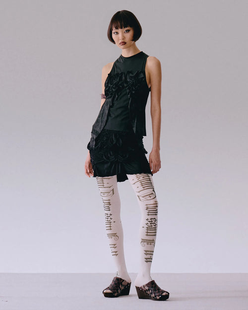 Model wearing black top with roses applique, fitted silhouette